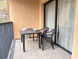 Ein kleiner Balkon mit Tisch und zwei Stühlen, einem Buch und zwei Tassen.