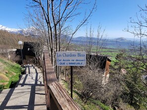 A sign with text in a foreign language, a wooden pathway, and a mountainous landscape in the background. - Central studio, pets welcome - 4 guests (Saint-Michel-de-Chaillol)