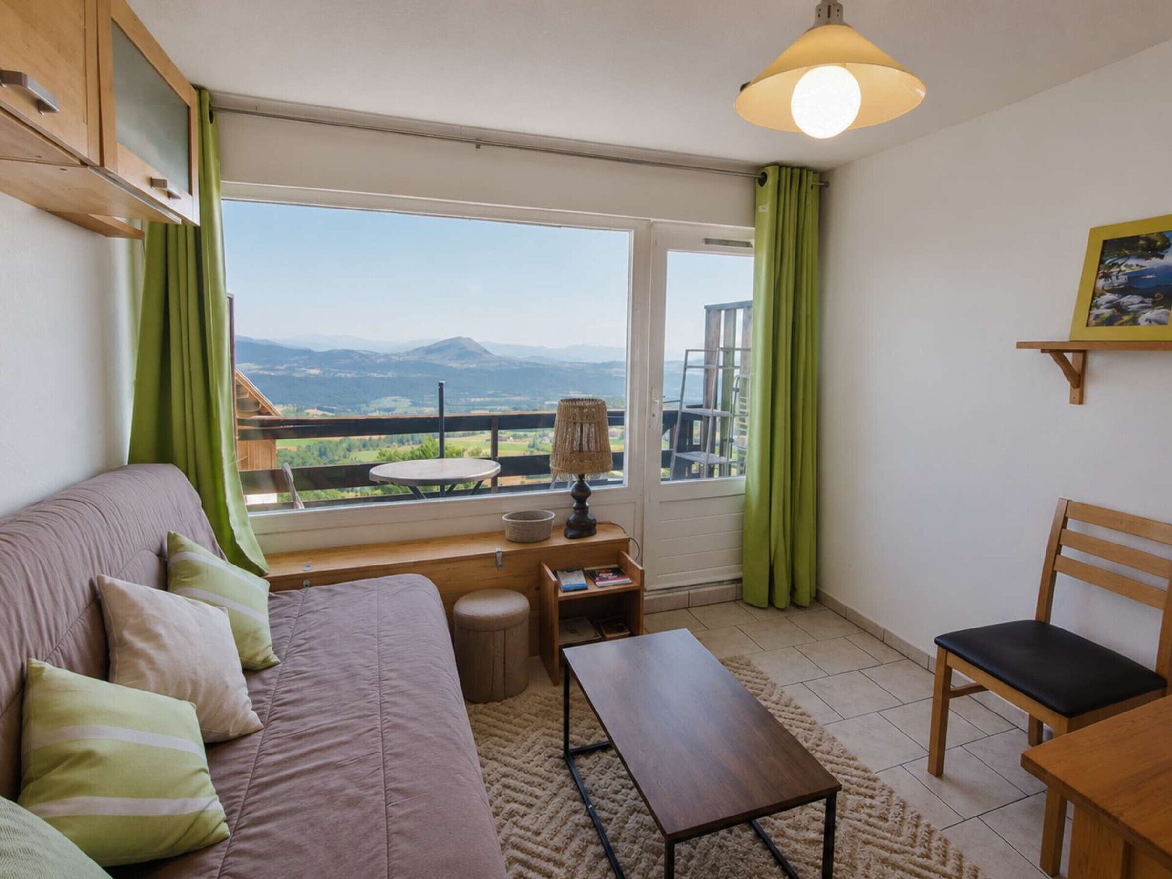A cozy room with a sofa, a table, a chair, and a view of the outdoors.