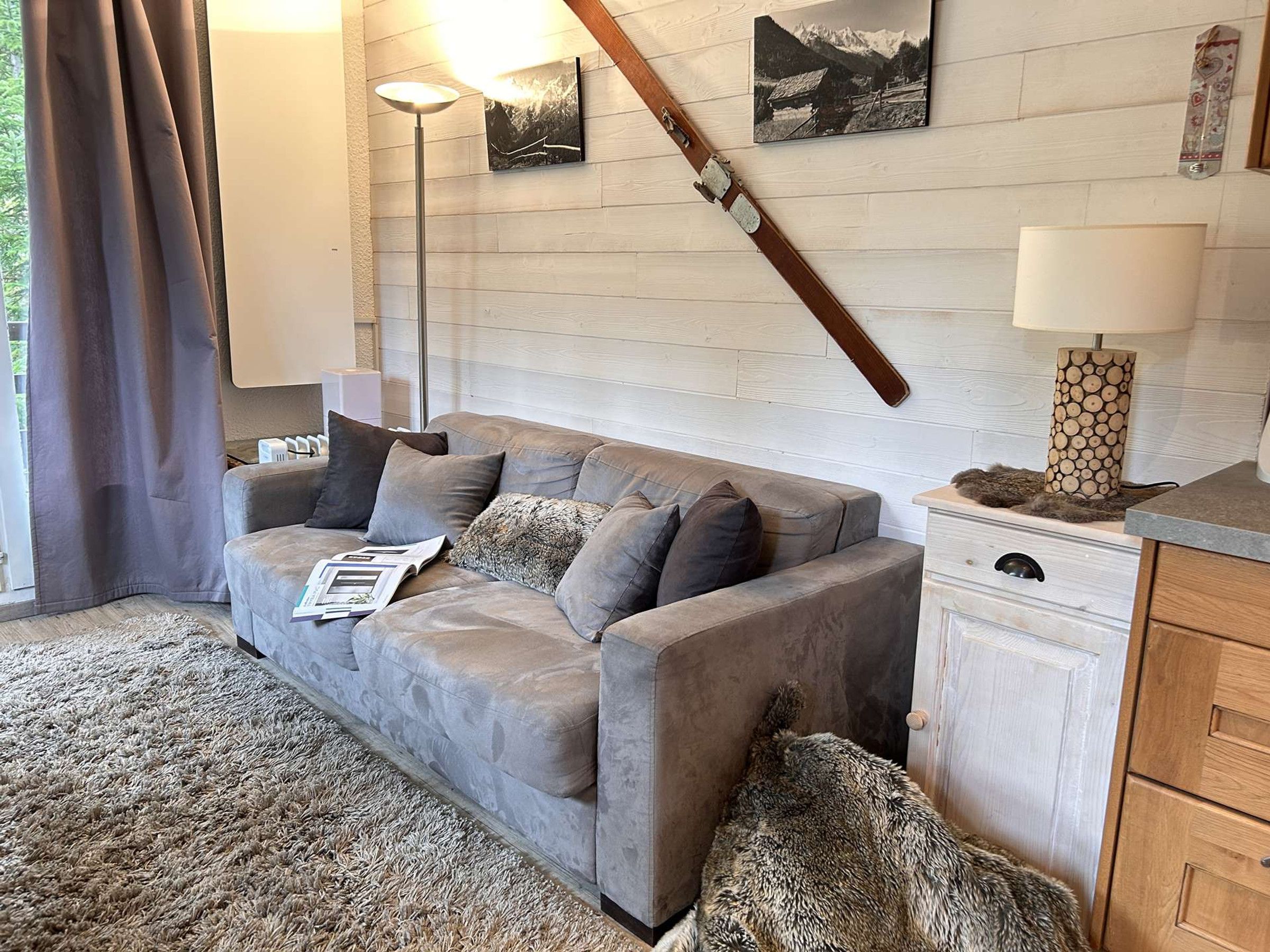 A living room with a sofa, pillows, a lamp, a fireplace, and a wall-mounted picture.