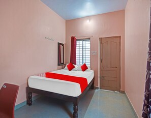 Un dormitorio con cama, ventana con cortinas, una puerta y un interruptor de luz en la pared.