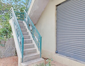 Un escalier avec une rampe métallique menant à l’entrée d’un bâtiment.