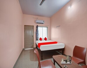 A bedroom with a bed, a window with curtains, a door, an air conditioning unit, and a small table with a tray. - Deluxe New Mayuri Lodge (Bagepalli)