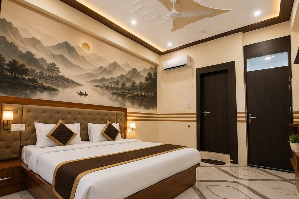 Habitación de hotel con una cama grande, un ventilador de techo, un aire acondicionado de pared y un mural de un paisaje montañoso.