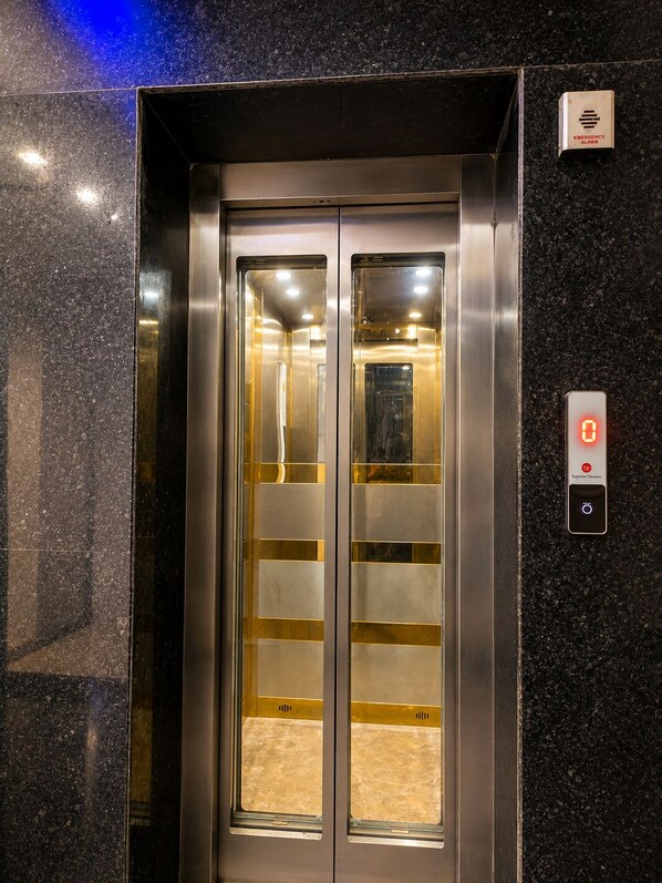 Un ascensor con pantalla digital y botón de alarma de emergencia.