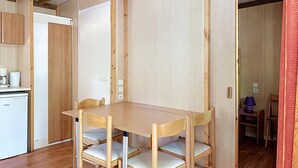 Una cocina compacta con una mesa y sillas de madera, una cafetera y un refrigerador.