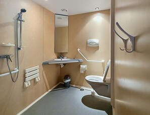 A bathroom with a shower, sink, toilet, and handrails. - Lakeside 2BR Chalet for Four (Moncontour)