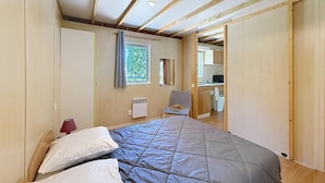 Un dormitorio con cama, una silla, un radiador y una ventana.