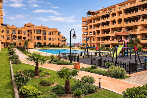 A residential building with a swimming pool, a playground, and a well-maintained garden.