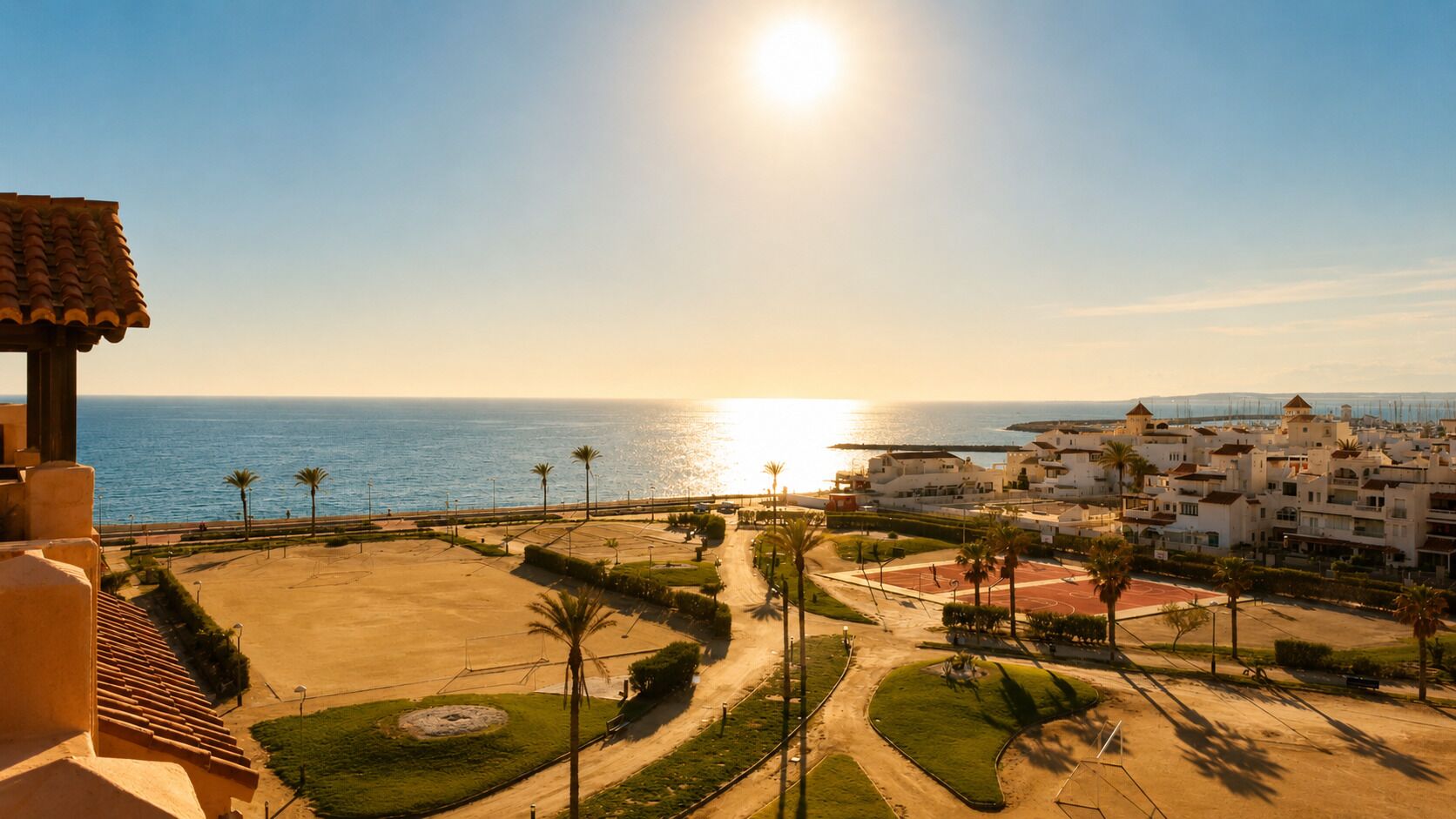 Zona residencial costera con playa, palmeras y cielo despejado.
