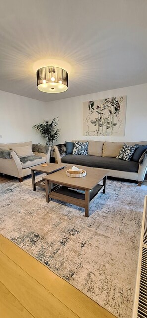 A living room with a sofa, a coffee table, and a floor lamp. - Moder home in quiet location With free parking, Close link to London, Zone 6 (Epsom)
