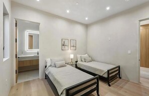 A bedroom with two single beds, a bedside table with a lamp, a mirror, and two framed pictures on the wall. - Curson Estate: Luxury Home with Pool, Spa & Home Theater (Los Angeles)