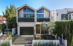 A modern two-story house with a garage, a sloped roof, and a well-maintained garden. - Curson Estate: Luxury Home with Pool, Spa & Home Theater (Los Angeles)