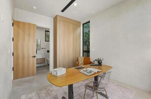 A modern interior with a wooden table, clear chairs, and a view of a bathroom. - Curson Estate: Luxury Home with Pool, Spa & Home Theater (Los Angeles)