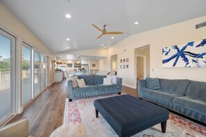 A spacious living area with a large sofa, a coffee table, and a patterned rug. - The Otter House on Happy Hill! Ocean Views & Short Walk to Moonstone Beach! (CAMBRIA)