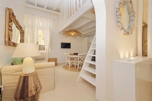 Un salon moderne comprenant un canapé, une lampe, un téléviseur et un coin repas avec des chaises et une table.