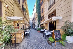 A narrow cobblestone street with outdoor seating and a chalkboard menu. - Vrbo Property (Roma)