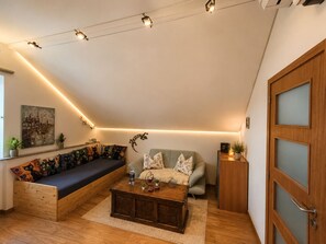 A cozy living room with a wooden bench, a sofa, a coffee table, and a door with frosted glass panels. - Bed & Breakfast (Penalva do Castelo)