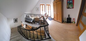 A staircase with a black railing leading to a living area with a sofa and a wooden cabinet. - Bed & Breakfast (Penalva do Castelo)