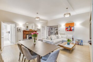 Ein modernes Wohnzimmer mit Essbereich, Kamin und Kunstwerken an den Wänden.