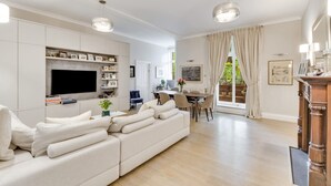 En moderne stue med en stor sofa, et fladskærms-tv og et spiseområde med et bord og stole.