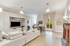 Ein modernes Wohnzimmer mit einer großen Couch, einem Flachbildfernseher und einem Essbereich mit Tisch und Stühlen.