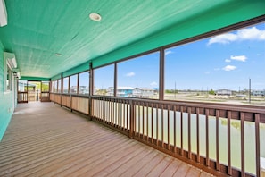 A covered outdoor deck with a view of the water and buildings in the distance. - Fall Special! Buy 2 nights, get your 3rd night Free! At Seaglass Smiles (Rockport)