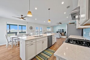 A modern kitchen with a central island, overhead lighting, and a view to the outside. - Fall Special! Buy 2 nights, get your 3rd night Free! At Seaglass Smiles (Rockport)