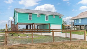 A two-story house with a covered porch and a garage. - SeaGlass Smiles | Canal-Front, Private Dock & Dog-Friendly (Rockport)