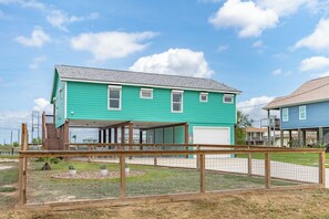 A two-story house with a covered porch and a garage. - SeaGlass Smiles | Canal-Front, Private Dock & Dog-Friendly (Rockport)