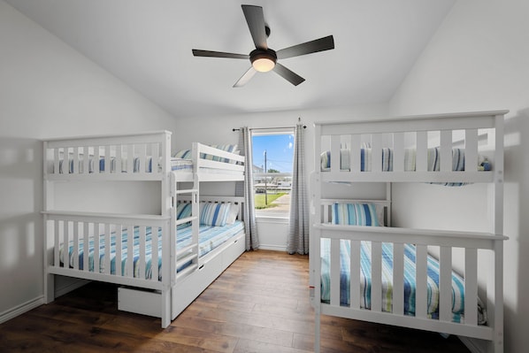A room with two bunk beds, a ceiling fan, and a window with curtains. - Fall Special! Buy 2 nights, get your 3rd night Free! At Seaglass Smiles (Rockport)