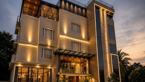 Un hotel de varios pisos con un diseño moderno, que cuenta con balcones, grandes ventanales y una entrada bien iluminada.