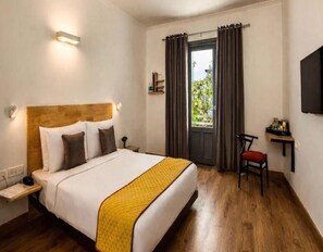 A hotel room with a bed, bedside table, chair, and a window with curtains. - Deluxe Room sn Bliss Premium Ladies pg (Bengaluru)