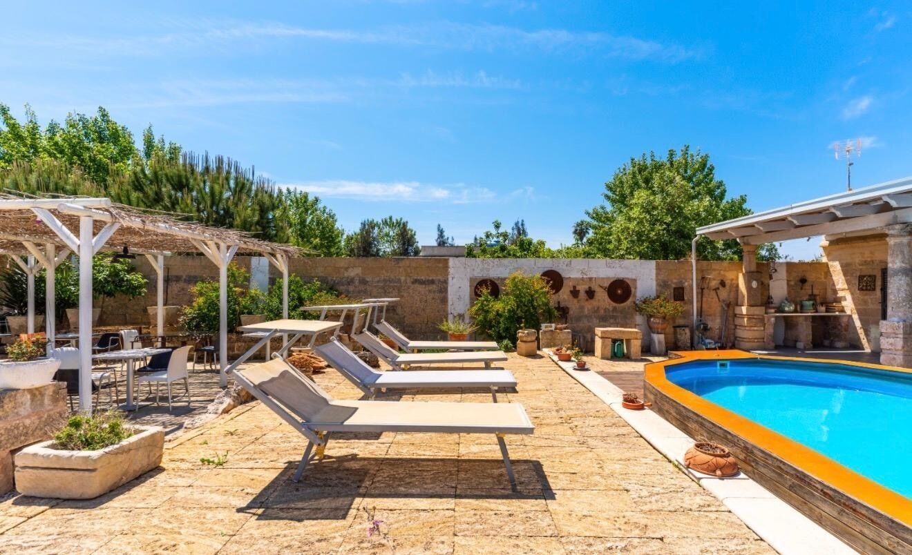 A poolside area with lounge chairs, tables, and a pergola.