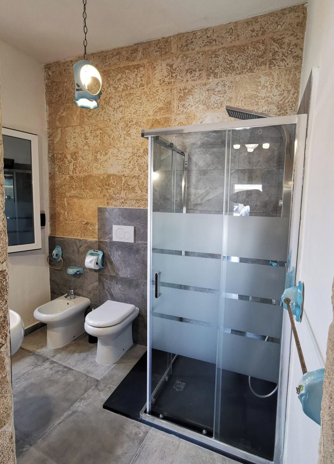 A modern bathroom with a glass-enclosed shower, a bidet, and a toilet.