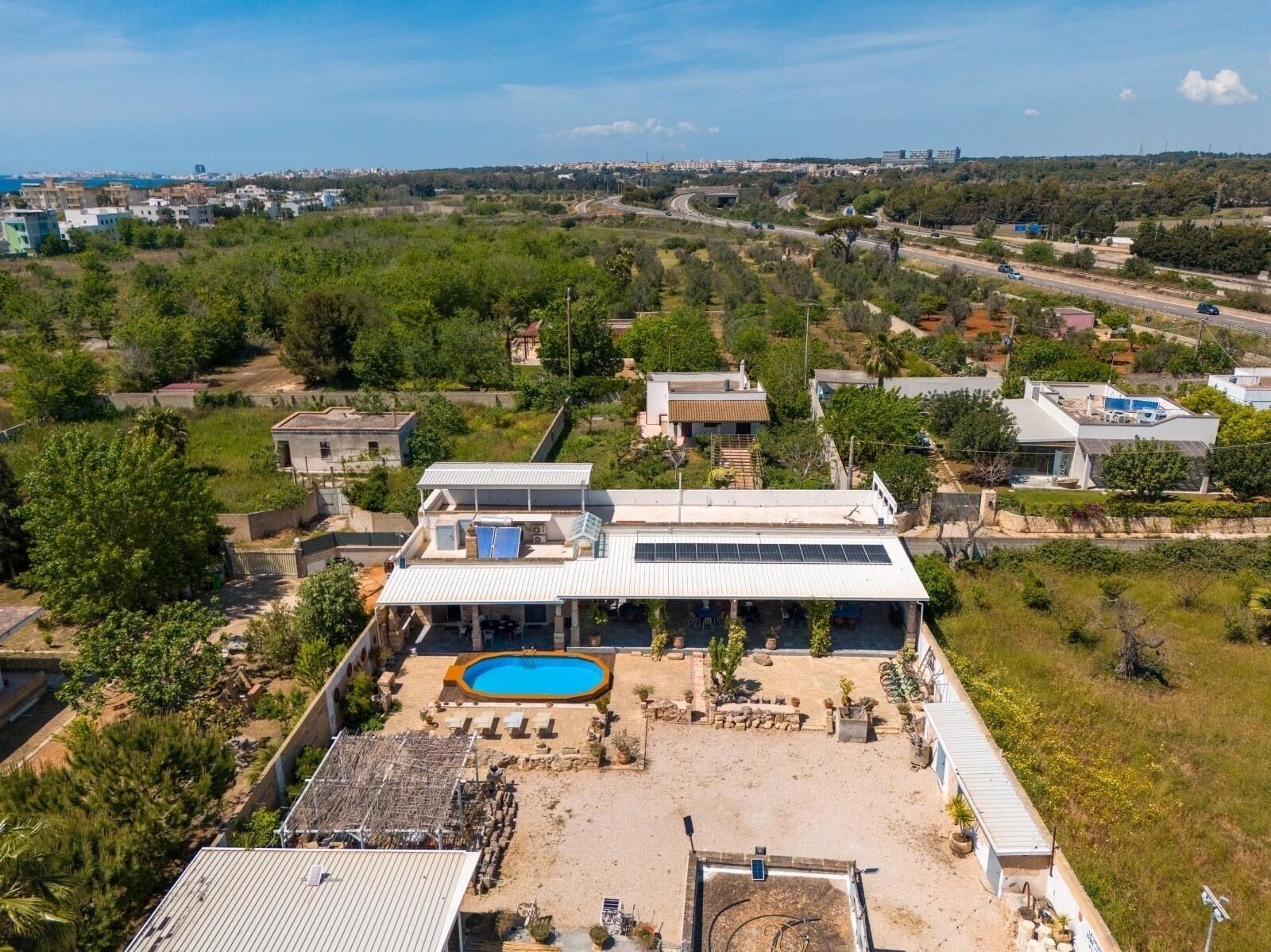 A modern house with a swimming pool, surrounded by greenery and a clear view of a cityscape in the distance.