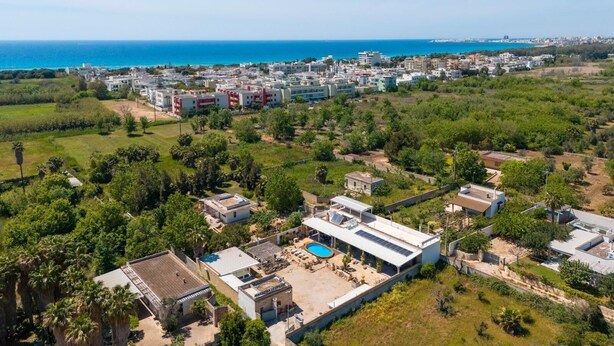 An aerial view of a coastal residential area with modern buildings, a swimming pool, and a clear view of the sea. - Elegant 19th-century farmhouse located 700 meters from Baia Verde, Gallipoli (Gallipoli)