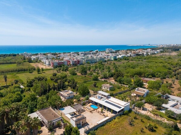 An aerial view of a coastal residential area with modern buildings, a swimming pool, and a clear view of the sea. - Elegant 19th-century farmhouse located 700 meters from Baia Verde, Gallipoli (Gallipoli)