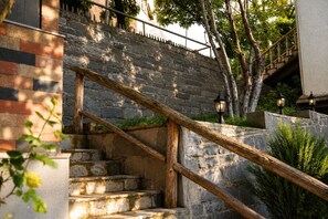 A stone staircase with wooden handrails and outdoor lighting fixtures.