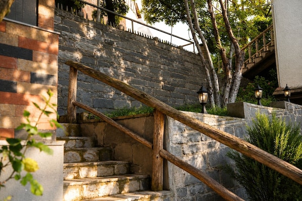 A stone staircase with wooden handrails and outdoor lighting fixtures.