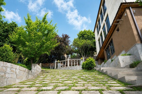 A stone staircase leading up to a building with a modern facade, surrounded by greenery and trees.