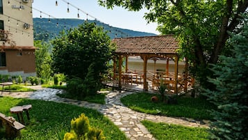 Un jardín con un pabellón, un sendero de piedra y mobiliario exterior.