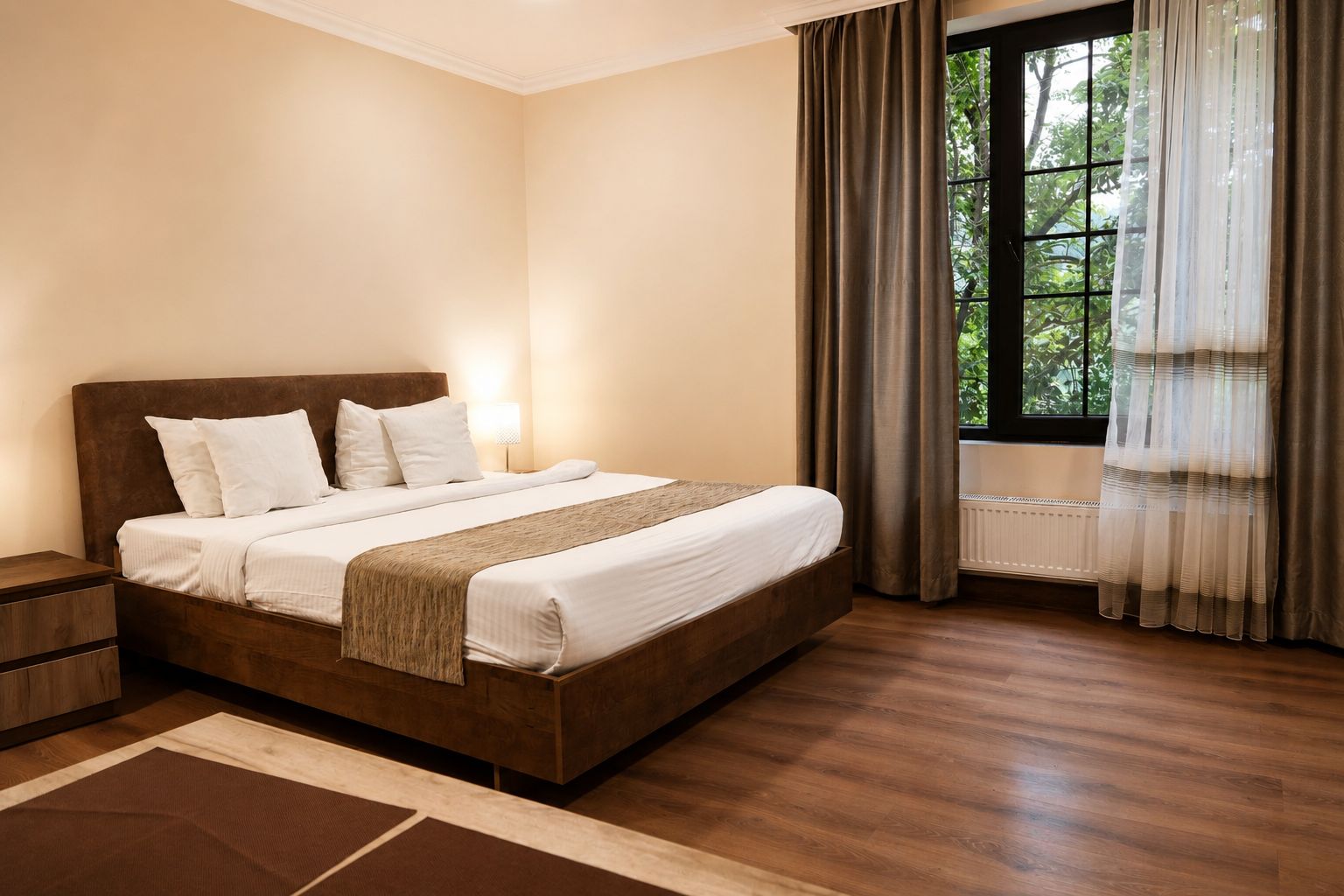 Un dormitorio con cama de madera, ropa de cama blanca, una mesita de noche, una ventana con cortinas y un radiador.