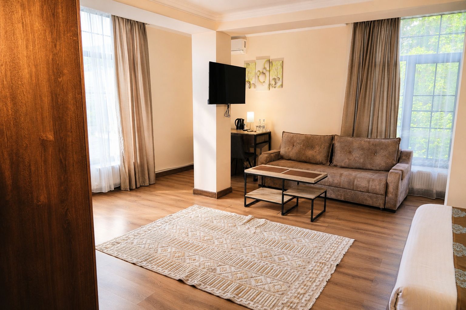 A living room with a sofa, a coffee table, a flat-screen TV, and a patterned rug.