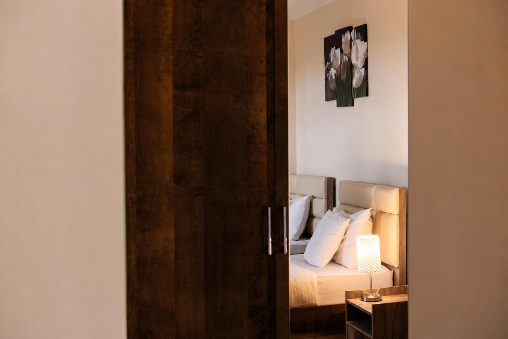 Un dormitorio con cama, mesita de noche, lámpara y un cuadro en la pared.