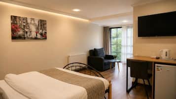 Habitación de hotel con cama, escritorio, silla, televisor y un cuadro en la pared.