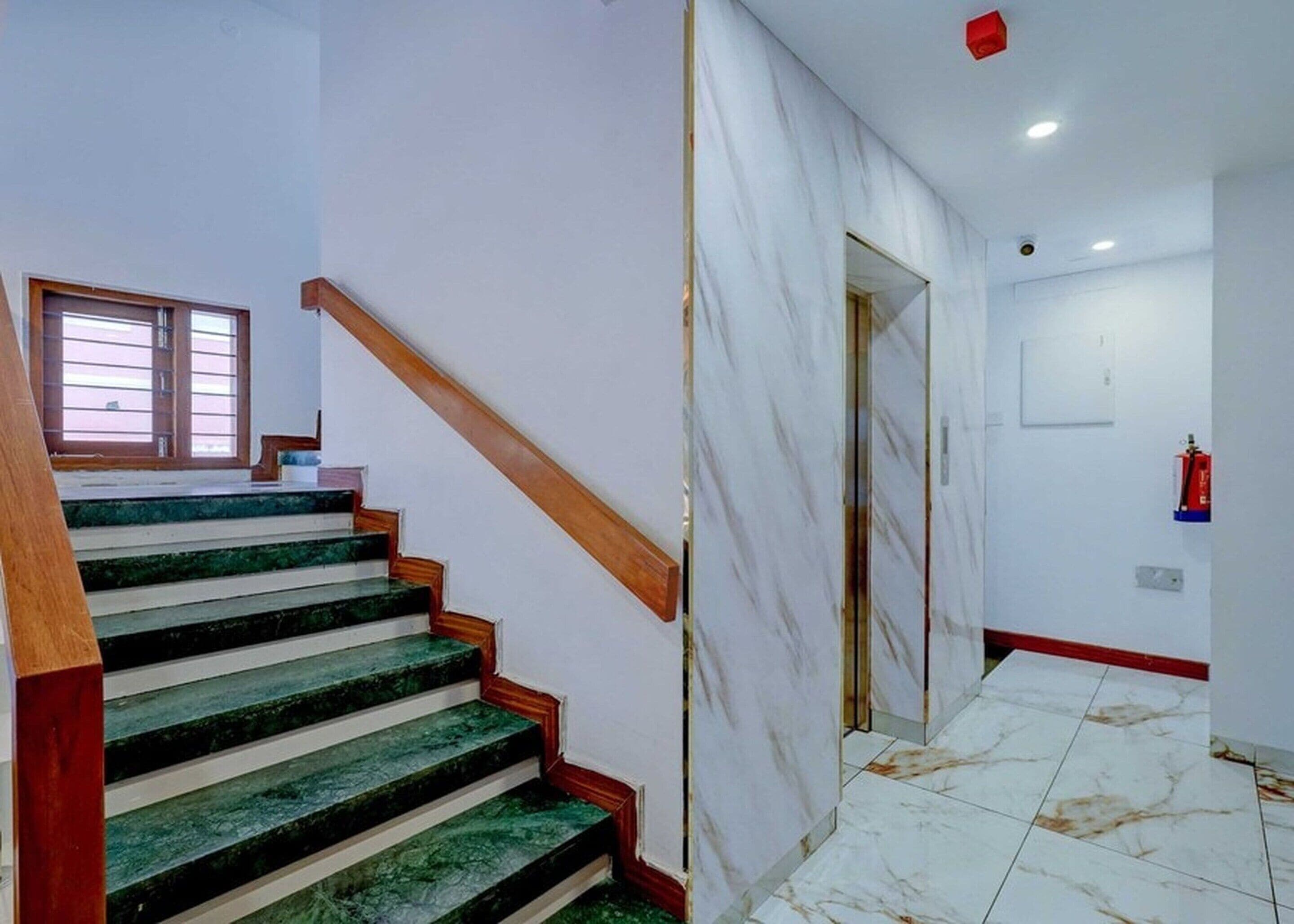 A staircase with wooden handrails and green marble steps leading to a landing.