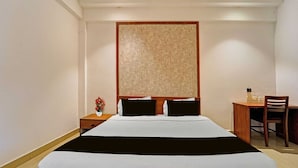 A hotel room with a bed, a desk, and a chair.