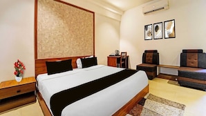 Ein Hotelzimmer mit einem großen Bett, einem Schreibtisch, einem Stuhl und einem kleinen Tisch.