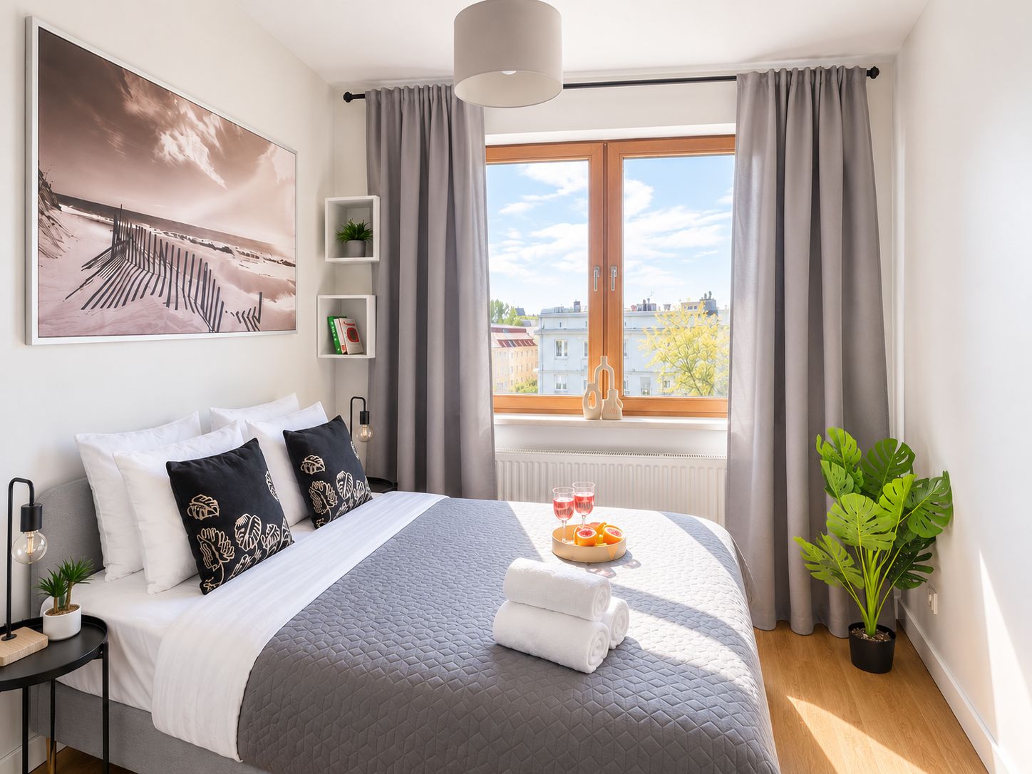A modern bedroom with a large bed, a view of the city, and a potted plant.